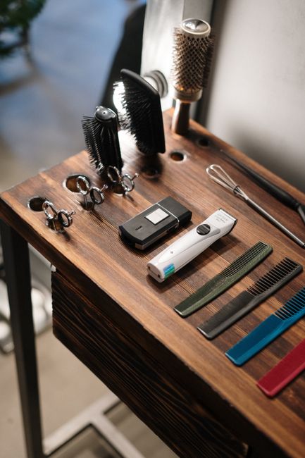 Barber tools including brushes and clippers on a wooden bench