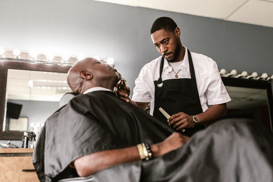 Barber trimming a client's beard with a straight razor